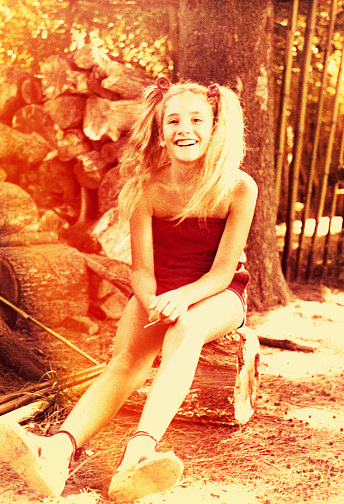 Vintage image from the seventies featuring a girl sitting outdoors and smiling.