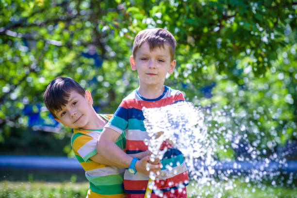 istock Brothers having fun splash each other with water in the village 963439326