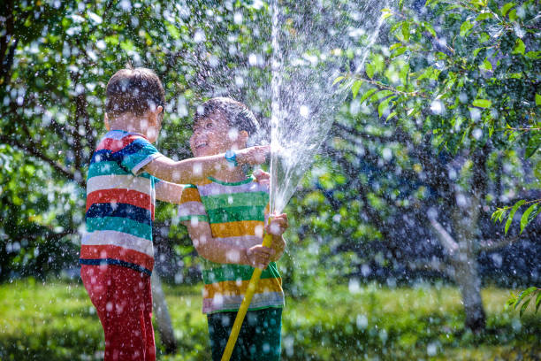 istock Happy boy pours water from a hose 963440046