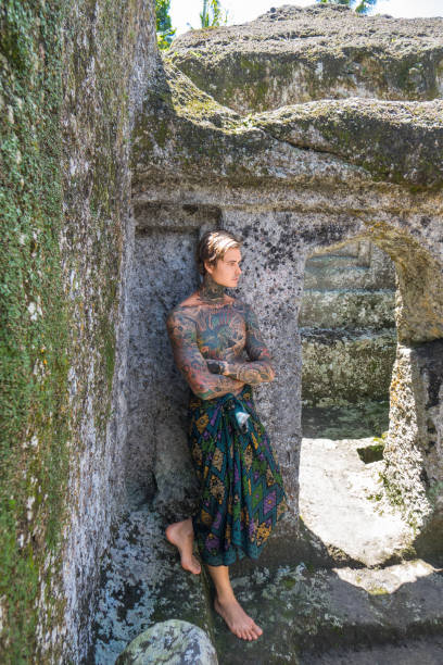 istock shirtless tattooed man standing at ruins in bali, indonesia 963447708