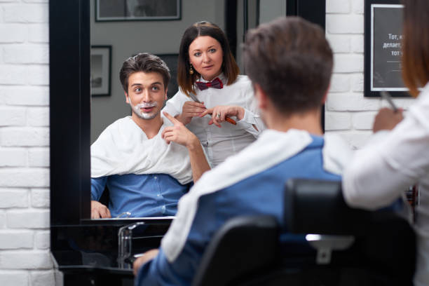istock The barber shaves beard with razor in barbershop 963447736