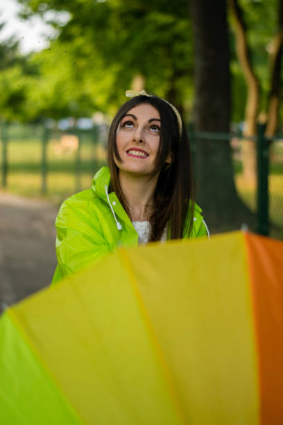 istock Young woman with raincoat holding rainbow colored umbrella 963448982