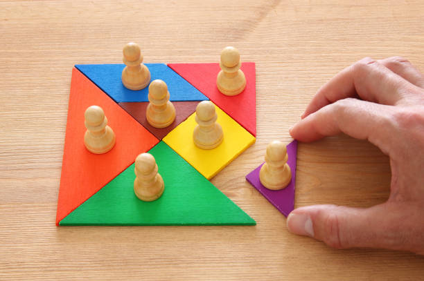 istock image of tangram puzzle blocks with chess figures over wooden table ,human resources and management concept. 963454020