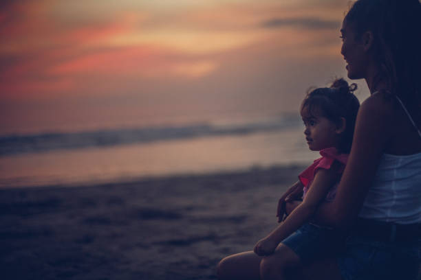 istock Mother and cute daughter enjoying sunset 963454724