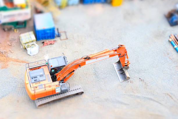Digger excavator construction building site view from above miniature rubber tracks orange vehicle in operation excavating uk