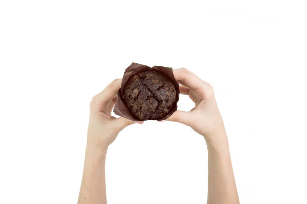 istock Hand Holding Black Cocoa Muffin With Chocolate Chips On It In Baking Paper Isolated Top View 963457874