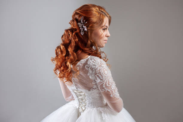 Portrait of a charming red-haired bride, Studio, close-up. Wedding hairstyle and makeup. Young woman in luxurious wedding dress