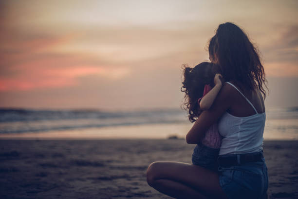 istock Mother and daughter relaxing at the beach 963458760