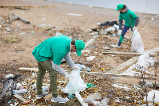 Fighting with trash Young staff in green uniform fighting with litter thrown on abandoned territory greenpeace activists stock pictures, royalty-free photos & images