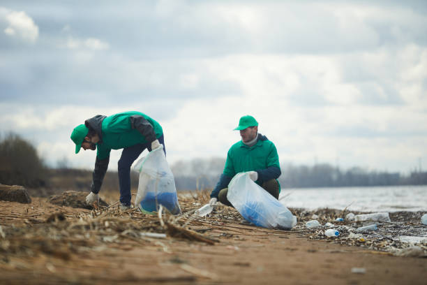 Working on river bank Ecology organization workers picking litter from dirty territory and utilizing it into special sacks greenpeace activists stock pictures, royalty-free photos & images