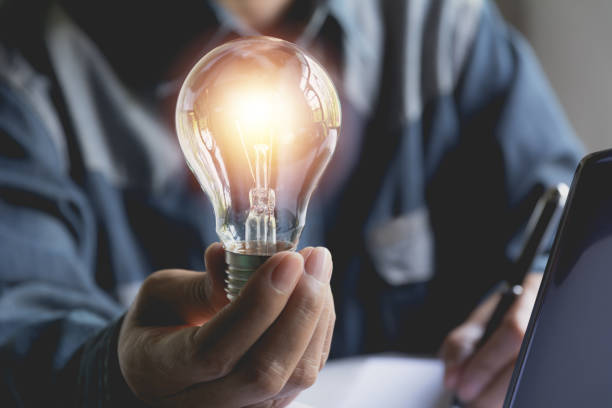 istock Hand of male holding a light bulb and using a laptop for accounting and creative concept. 963463766