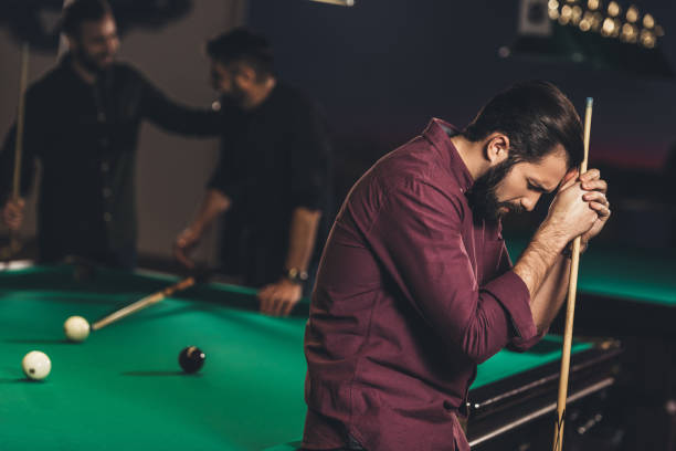istock upset caucasian man with cue beside pool table at bar with friends 963507302
