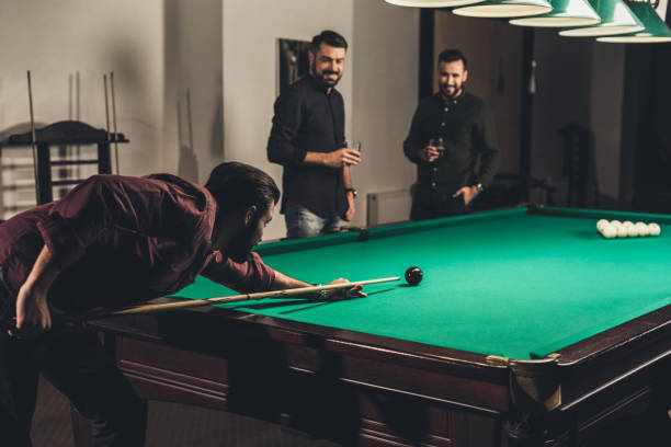 istock successful man playing in pool at bar with friends 963509588