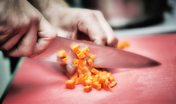 istock Man slicing carrots on cutting board in kitchen 963509802