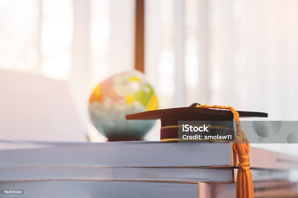 A obtenu son diplôme ou diplôme Université étudier à l’étranger conceptuel international, Master PAC sur pile de livres avec le flou d’Amérique terre globe modèle mappemonde dans la salle de la bibliothèque du campus, retour à l’école - Photo de Étudier libre de droits