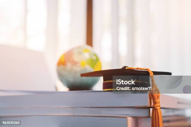 Graduated Or Graduation University Study Abroad International Conceptual Master Cap On Books Stack With Blur Of America Earth World Globe Model Map In Library Room Of Campus Back To School Stock Photo - Download Image Now