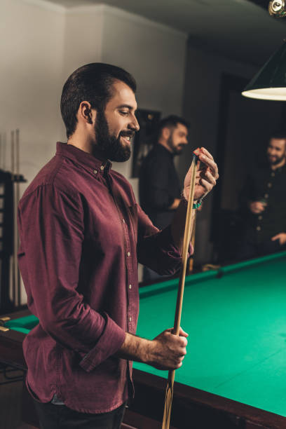 istock handsome man rubbing cue with chalk at bar with friends 963514722