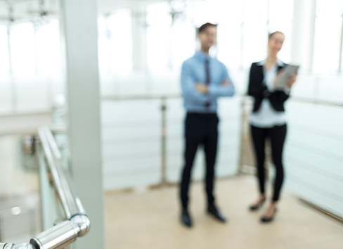 Steel detail of handrail in modern workplace, focus on foreground. On background couple coworkers.