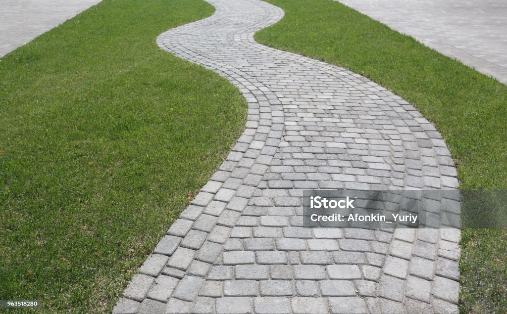 Courbe de chemin d’accès sous la forme d’une vague sur l’herbe dans le parc. Pavé de carreaux de formes différentes. - Photo de Voie piétonne libre de droits