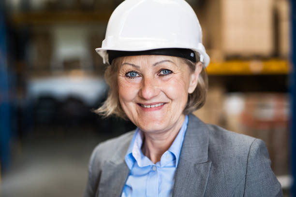 istock Senior woman warehouse manager or supervisor with white helmet. 963524242
