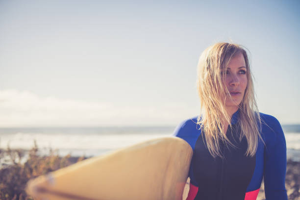 Young female surfer at the beach; Playa Las Americas, Tenerife. Europe / Africa. Nikon D850, All logos removed.