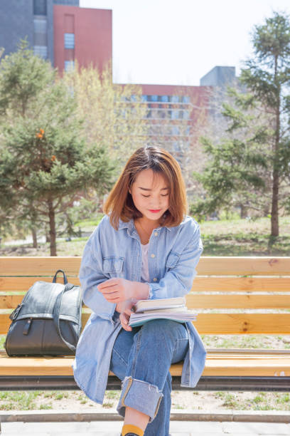 istock Student reading books and sitting on the bench in an university campus 963530012
