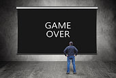 Man stands in front of black screen with words Game Over