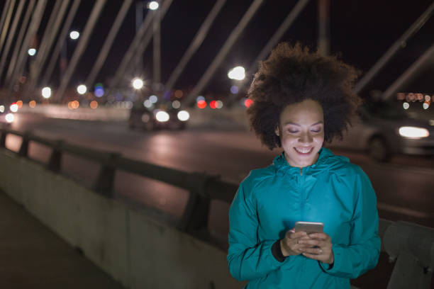 istock Woman exercising and using phone outdoors at night 963535654