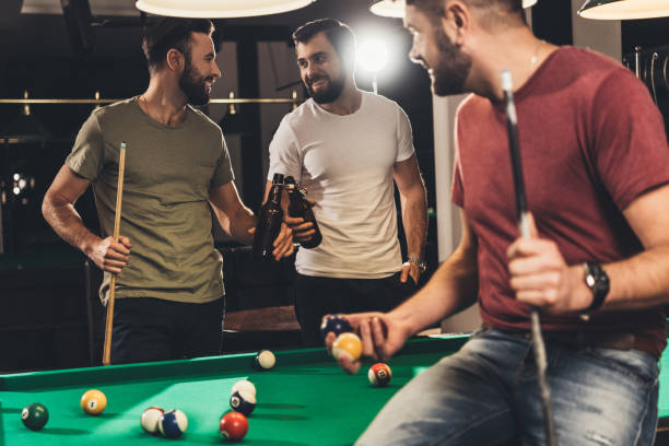 young caucasian men drinking beer beside billiard table in bar - pool game imagens e fotografias de stock