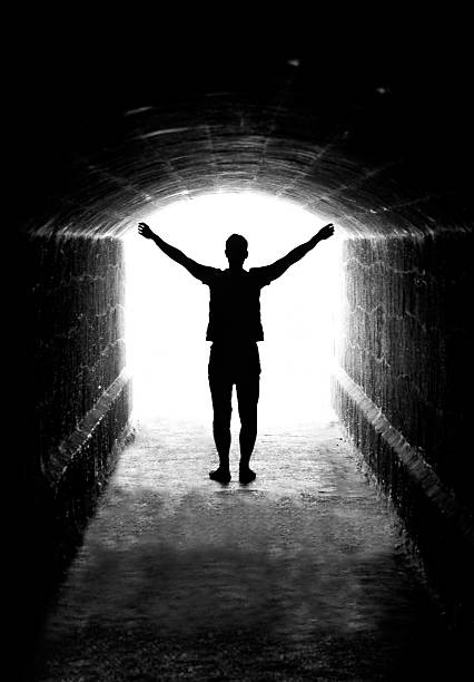 istock A silhouette of a man with his hands up near a tunnel exit 96354967