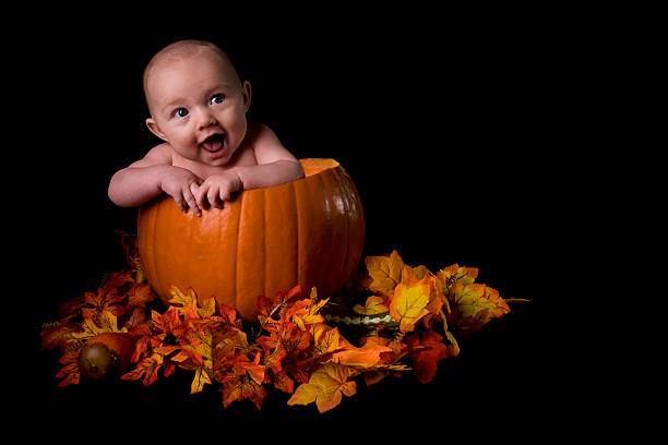 Baby in Large Pumpkin Isolated on Black stock photo