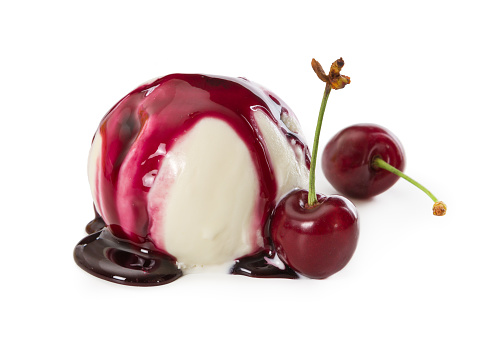 Vanilla ice cream ball with fresh cherries and cherry syrup isolated on white background.