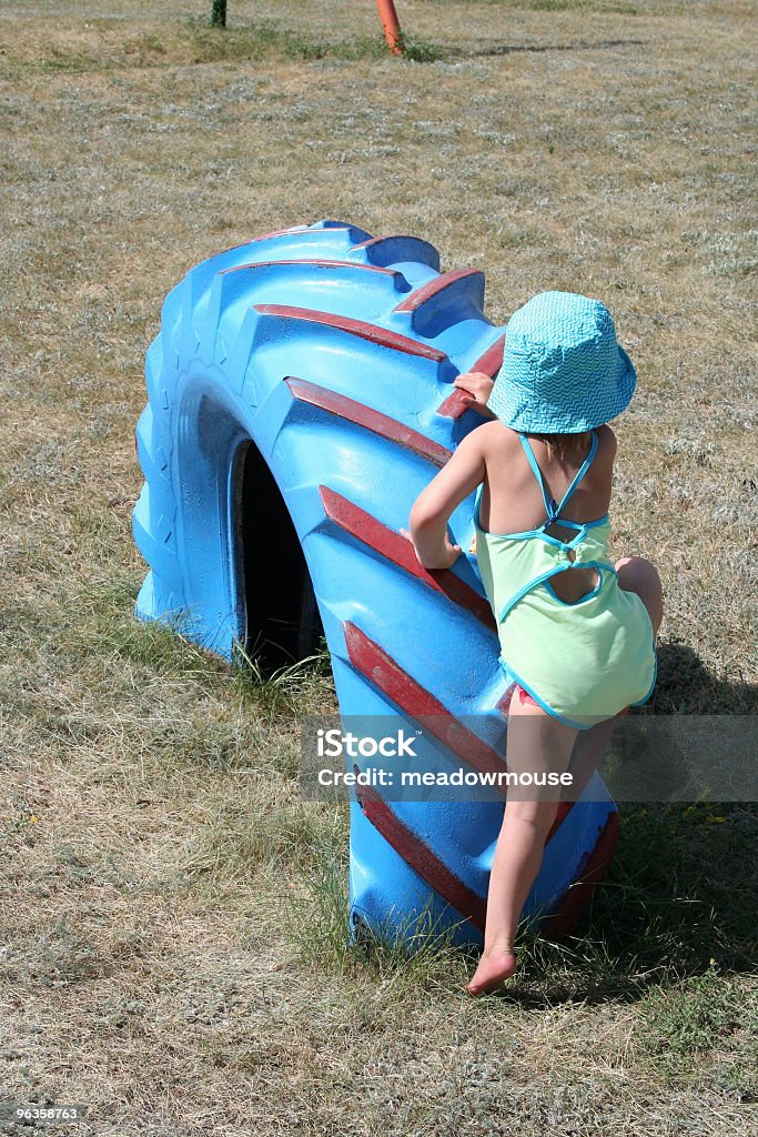 little girl in swimming costume ascensions immense terrain de jeu de pneu - Photo de 2-3 ans libre de droits