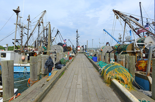 Maritime scene with commercial fishing boats in water near dock before sailing into the ocean