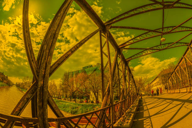 Timisoara: Old and new together.The modernist NOKIA building seen from an old pedestrian metal bridge designed by Gustave Eiffel and a view along the Bega River at sunset time