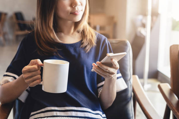 istock Young woman using smart phone in coffee shop drinking coffee 963677080