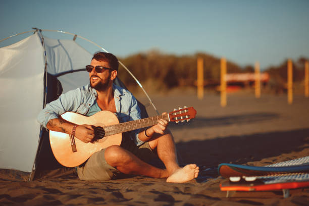 Asian man playing a ukulele and singing with enjoy on a tropical beach, Live life happily on holidays.