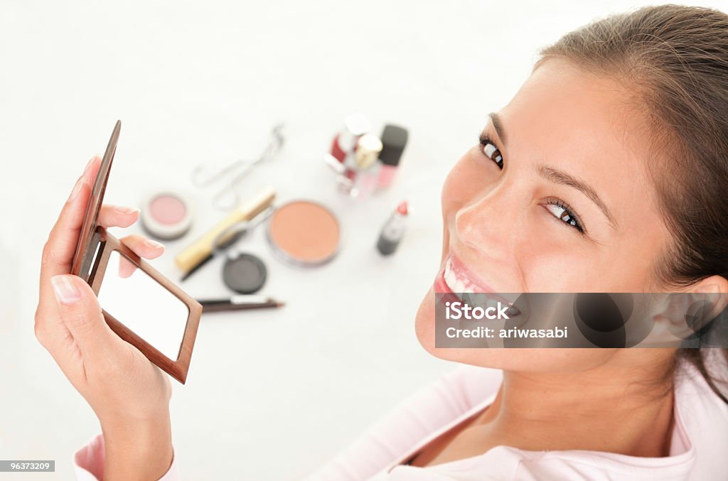 Donna sorridente con cosmetici e specchio - Foto stock royalty-free di Accudire