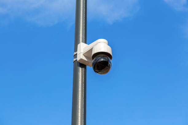 istock Surveillance CCTV camera mounted on post against the blue sky 963798288