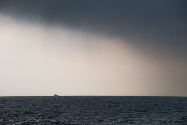 Rain at the sea with a sailboat in distance.