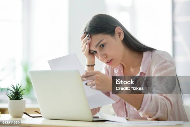 Worried Frustrated Woman Shocked By Bad News While Reading Letter Stock Photo - Download Image Now