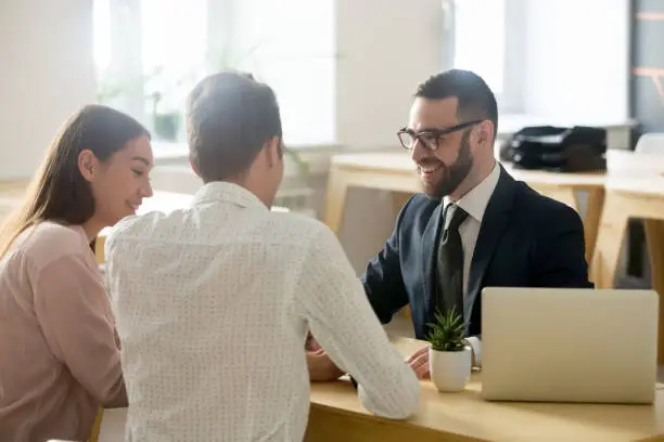 Photo of Friendly lawyer or financial advisor in suit consulting young couple