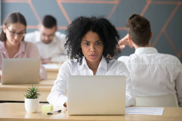 shocked african-american woman looking at laptop stressed with online news - female emotional stress african ethnicity loss imagens e fotografias de stock