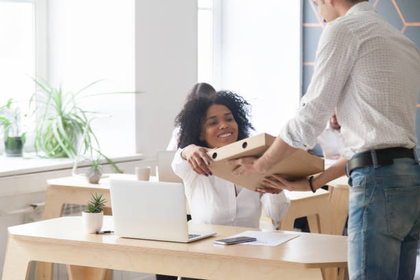 smiling african employee taking pizza from courier, office food delivery - pizza eating african descent lunch imagens e fotografias de stock