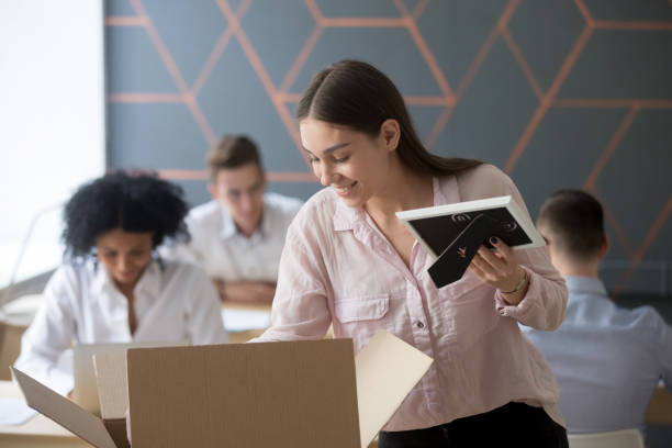 istock Smiling new female employee unpacking box at workplace in office 963814510