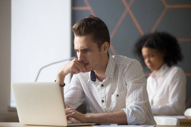 istock Puzzled serious male employee solving online laptop problem in office 963815278