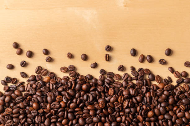 istock Spilled fresh coffee beans on blonde wooden table 963821136