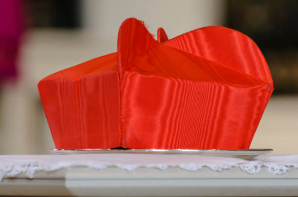 il cappello beretta di un cardinale si siede su un tavolo durante una messa di requiem - cardinale clero immagine foto e immagini stock