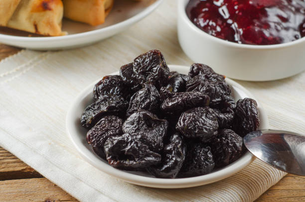Prunes on small plate with jam from the plums on wooden table. Dried Plums. Healthy and vegetarian food Prunes on small plate with jam from the plums on a wooden table. Dried Plums. Healthy and vegetarian food. prune stock pictures, royalty-free photos & images