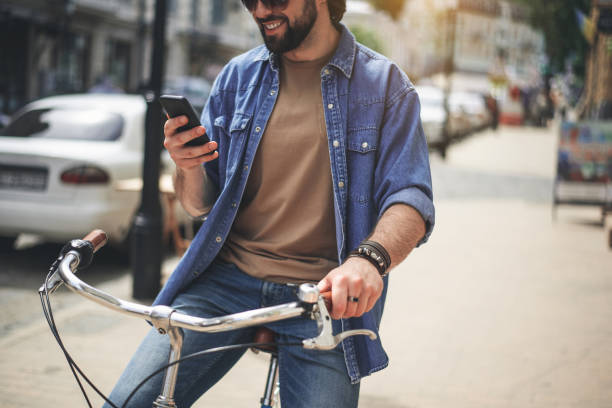 istock Satisfied young man taking seat on bicycle with phone 963842772